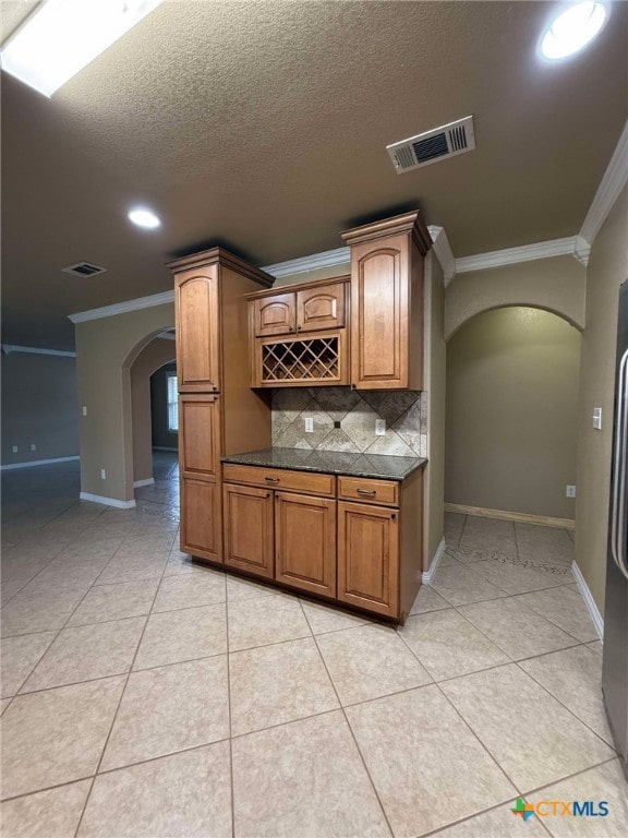 kitchen with crown molding, light tile patterned flooring, tasteful backsplash, and a textured ceiling