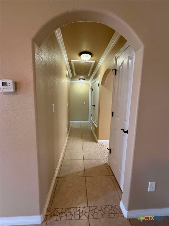 corridor with arched walkways, light tile patterned floors, baseboards, and crown molding