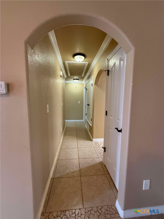 hall featuring arched walkways, light tile patterned flooring, crown molding, and baseboards