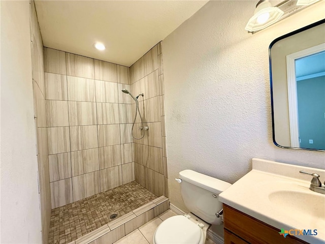 bathroom featuring vanity, toilet, and a tile shower