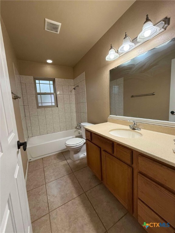 full bathroom with tiled shower / bath, vanity, toilet, and tile patterned flooring