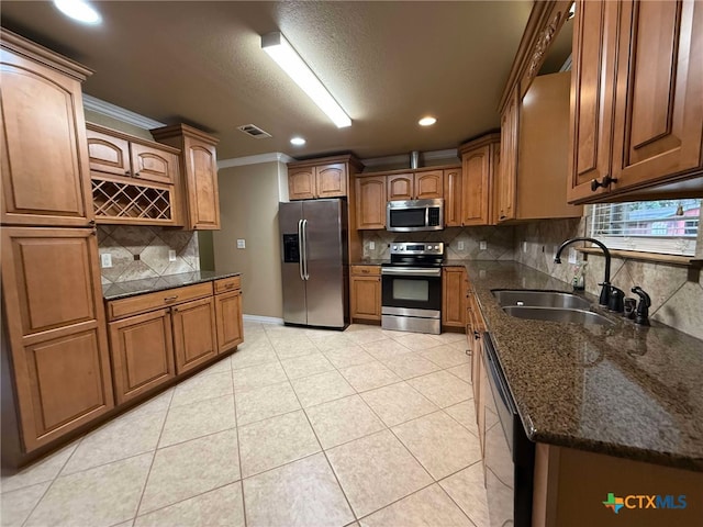 kitchen featuring light tile patterned flooring, appliances with stainless steel finishes, sink, decorative backsplash, and crown molding