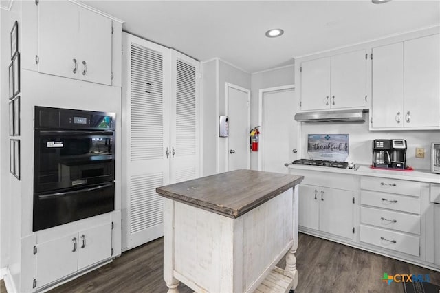 4811 Lilac Ln, Victoria, TX 77904 - kitchen featuring oven, a warming drawer, under cabinet range hood, dark wood-style floors, and white cabinetry