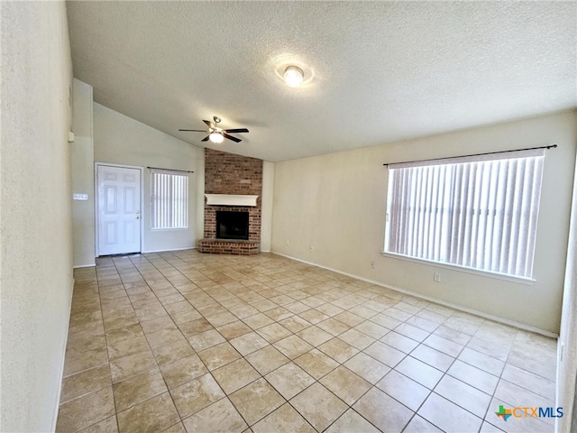 unfurnished living room with lofted ceiling, a textured ceiling, light tile patterned floors, and a brick fireplace