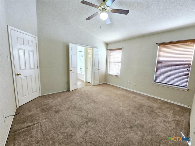 unfurnished bedroom with carpet, a textured ceiling, ceiling fan, connected bathroom, and lofted ceiling