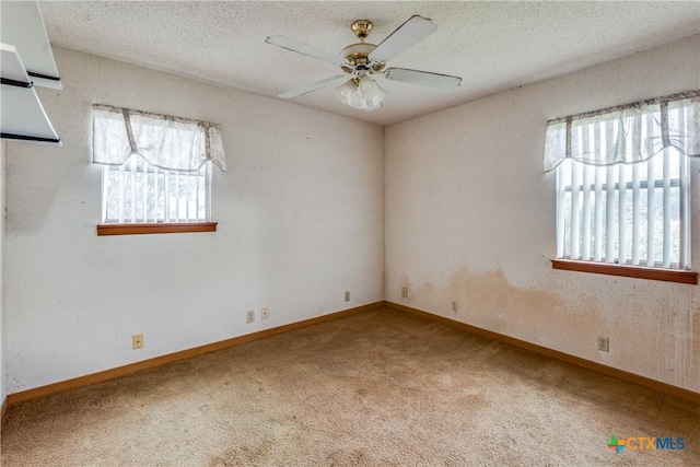 carpeted empty room featuring ceiling fan, a textured ceiling, and a wealth of natural light
