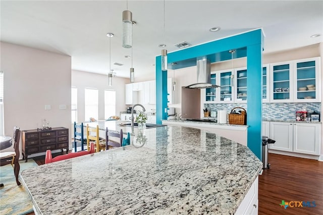 kitchen featuring pendant lighting, sink, white cabinetry, extractor fan, and a large island with sink