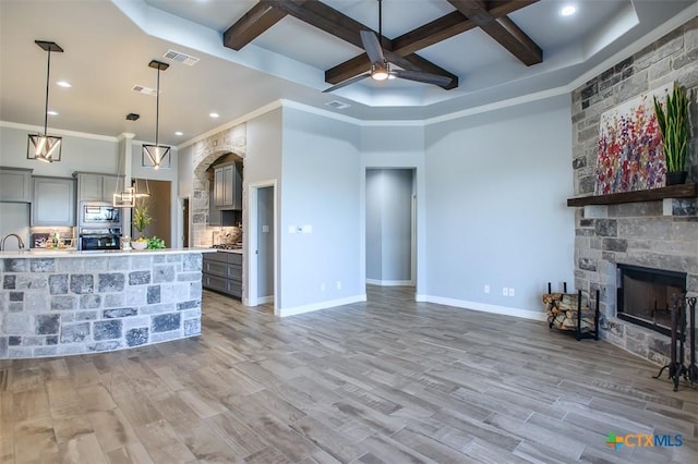 809 Reston Rd, Temple, TX 76502 - unfurnished living room with coffered ceiling, ceiling fan, a stone fireplace, beamed ceiling, and light wood-type flooring