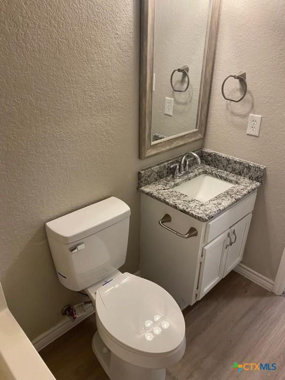 bathroom featuring wood-type flooring, vanity, and toilet