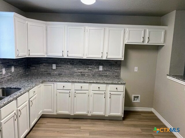 kitchen featuring light stone counters, white cabinetry, and tasteful backsplash