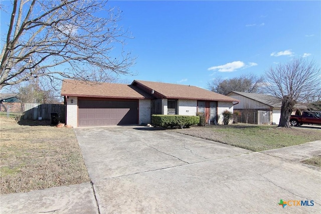 single story home with brick siding, an attached garage, driveway, and fence