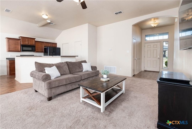 living area with visible vents, arched walkways, and light carpet