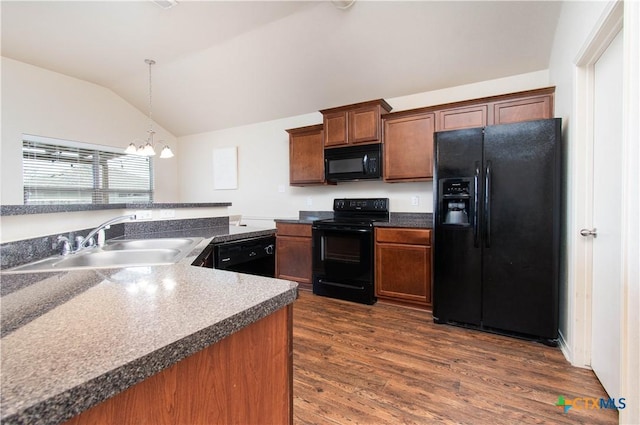 kitchen featuring black appliances, a sink, dark wood finished floors, vaulted ceiling, and hanging light fixtures