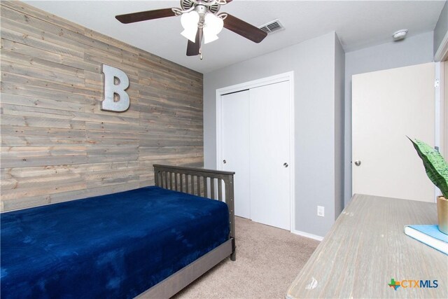 bedroom featuring visible vents, carpet floors, a closet, wood walls, and an accent wall