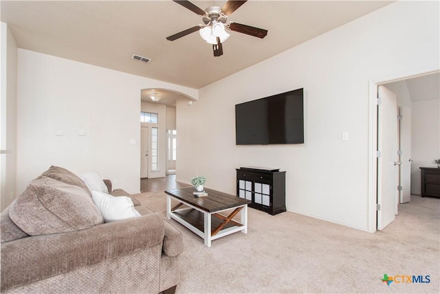 living area with a ceiling fan, carpet flooring, arched walkways, and visible vents