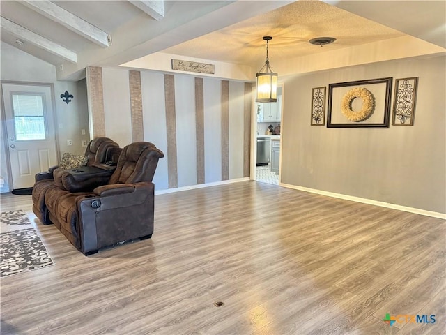 interior space featuring vaulted ceiling with beams, wood finished floors, visible vents, and baseboards