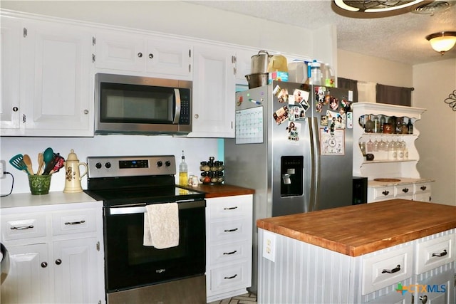 kitchen featuring stainless steel appliances, butcher block countertops, and white cabinetry