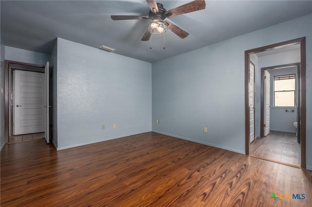 unfurnished bedroom featuring ceiling fan, dark wood-type flooring, and connected bathroom