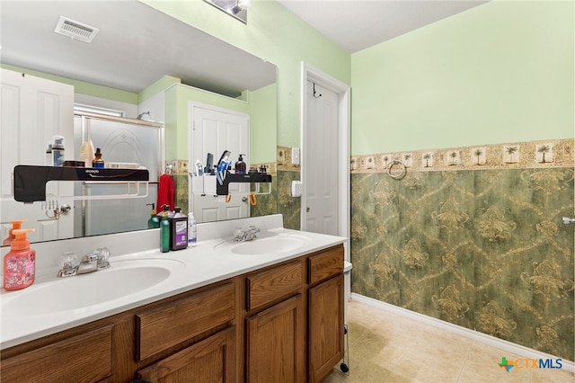 3628 Tilden Trl, New Braunfels, TX 78132 - bathroom with double vanity, a shower with shower door, tile patterned floors, and a wainscoted wall