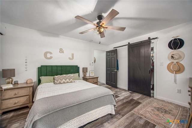 807 W Dallas Ave, Seadrift, TX 77983 - bedroom with a barn door, ceiling fan, baseboards, and wood finished floors