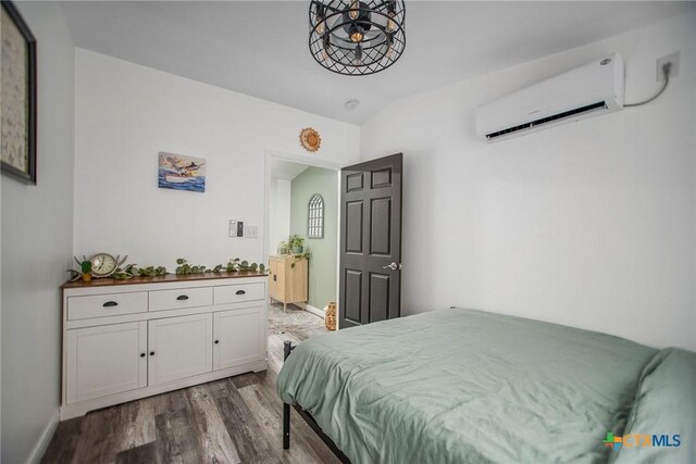 807 W Dallas Ave, Seadrift, TX 77983 - bedroom with baseboards, a wall unit AC, and dark wood finished floors