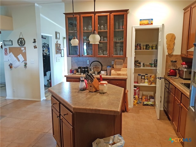 kitchen featuring decorative backsplash, a center island, decorative light fixtures, and light tile patterned flooring