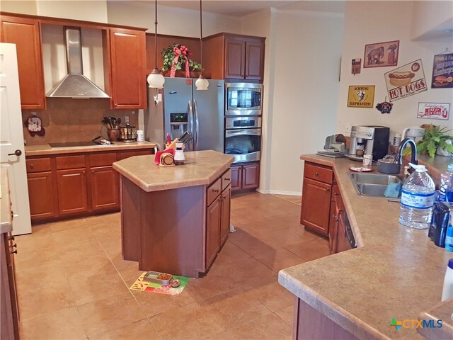 kitchen featuring stainless steel appliances, sink, wall chimney range hood, pendant lighting, and a kitchen island