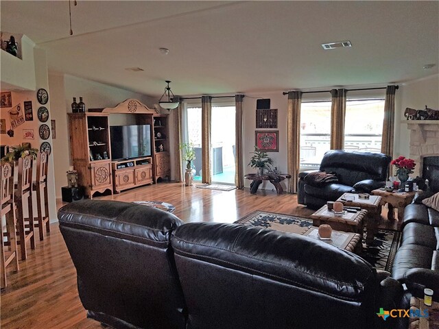 living room featuring a stone fireplace and light hardwood / wood-style flooring