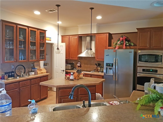 kitchen featuring sink, wall chimney range hood, tasteful backsplash, decorative light fixtures, and appliances with stainless steel finishes