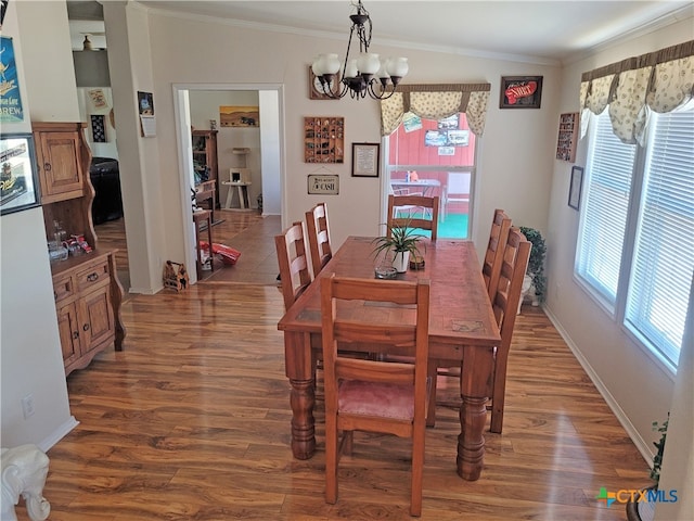 dining space with a chandelier, ornamental molding, and dark wood-type flooring