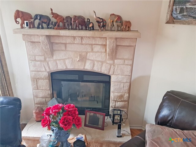 interior details featuring hardwood / wood-style floors and a stone fireplace