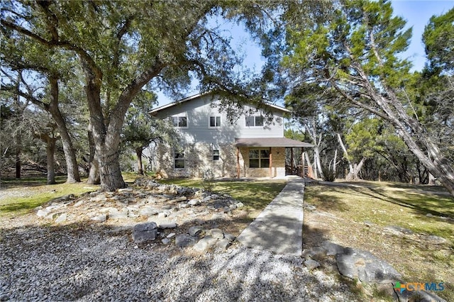 view of front of home featuring a front yard, covered porch, and brick siding