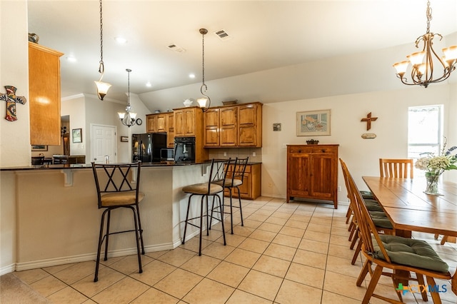 kitchen featuring black fridge, decorative light fixtures, a kitchen bar, kitchen peninsula, and lofted ceiling