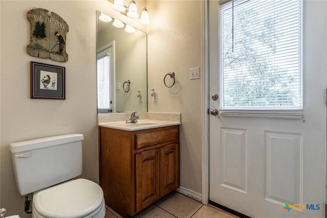 bathroom with vanity, a wealth of natural light, tile patterned flooring, and toilet