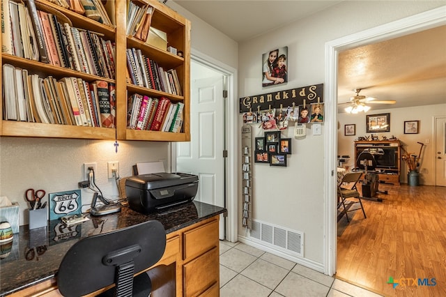 office area with light wood-type flooring, built in desk, and ceiling fan