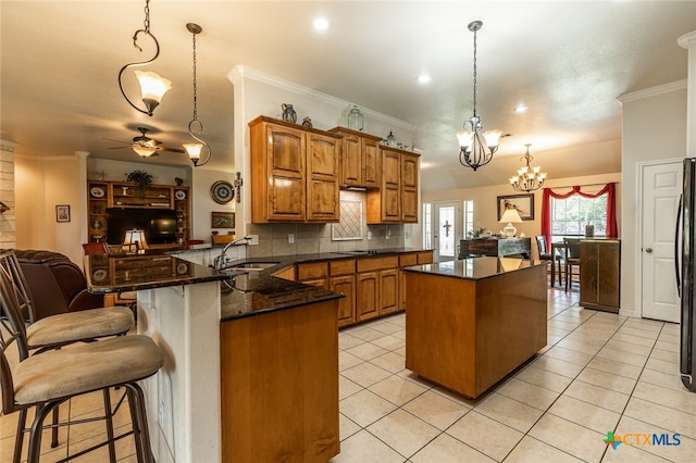 kitchen with ornamental molding, hanging light fixtures, sink, kitchen peninsula, and ceiling fan with notable chandelier