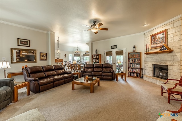 living room with a stone fireplace, light colored carpet, ceiling fan, and crown molding