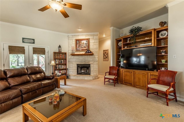 1199 Frederick Ln, Temple, TX 76502 - living area with ceiling fan, light colored carpet, crown molding, a stone fireplace, and french doors
