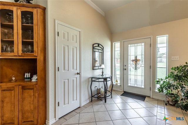 foyer entrance with vaulted ceiling, light tile patterned floors, and crown molding