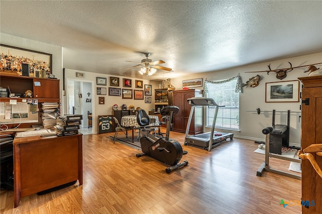 workout area featuring light hardwood / wood-style floors, a textured ceiling, and ceiling fan