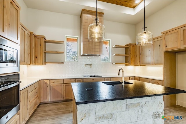 kitchen featuring sink, appliances with stainless steel finishes, an island with sink, pendant lighting, and decorative backsplash