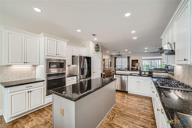 kitchen with backsplash, white cabinets, a center island, and stainless steel appliances