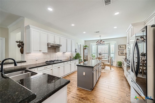 kitchen featuring pendant lighting, appliances with stainless steel finishes, a kitchen island, white cabinetry, and sink