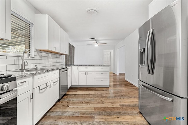 kitchen featuring light hardwood / wood-style flooring, stone countertops, appliances with stainless steel finishes, tasteful backsplash, and white cabinetry