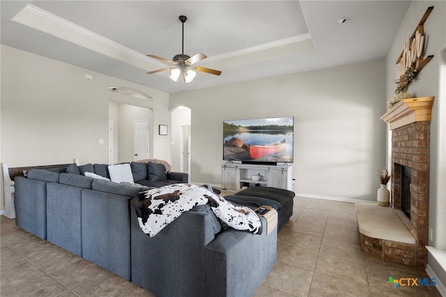 living room featuring a fireplace, a raised ceiling, ceiling fan, and light tile patterned flooring