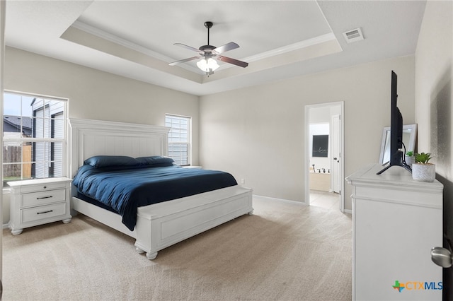 carpeted bedroom with a tray ceiling, ensuite bath, ceiling fan, and crown molding