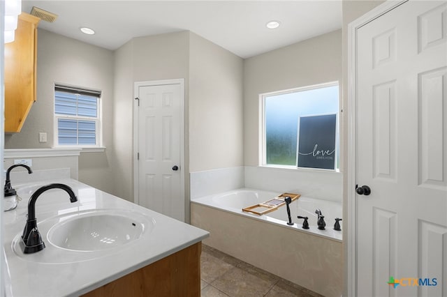 bathroom featuring a bathtub, vanity, a healthy amount of sunlight, and tile patterned flooring