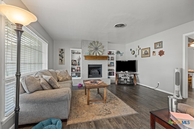 living room with a large fireplace, dark hardwood / wood-style flooring, and built in shelves