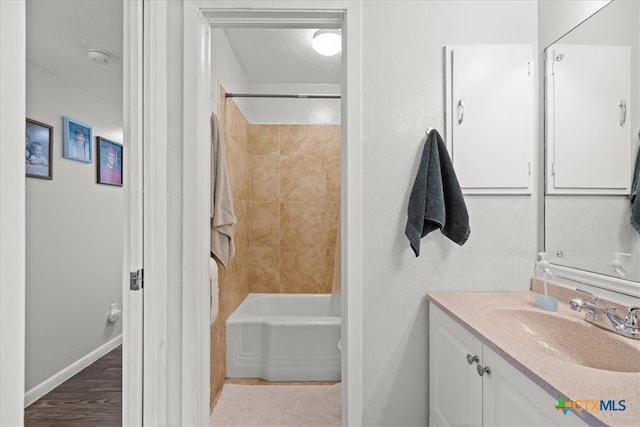 bathroom featuring wood-type flooring, tiled shower / bath combo, and vanity