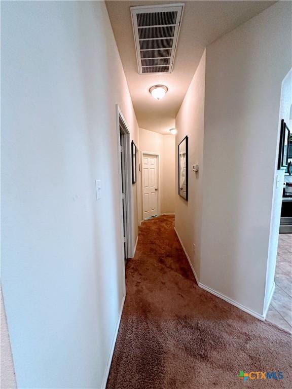 hall with light carpet, visible vents, and baseboards